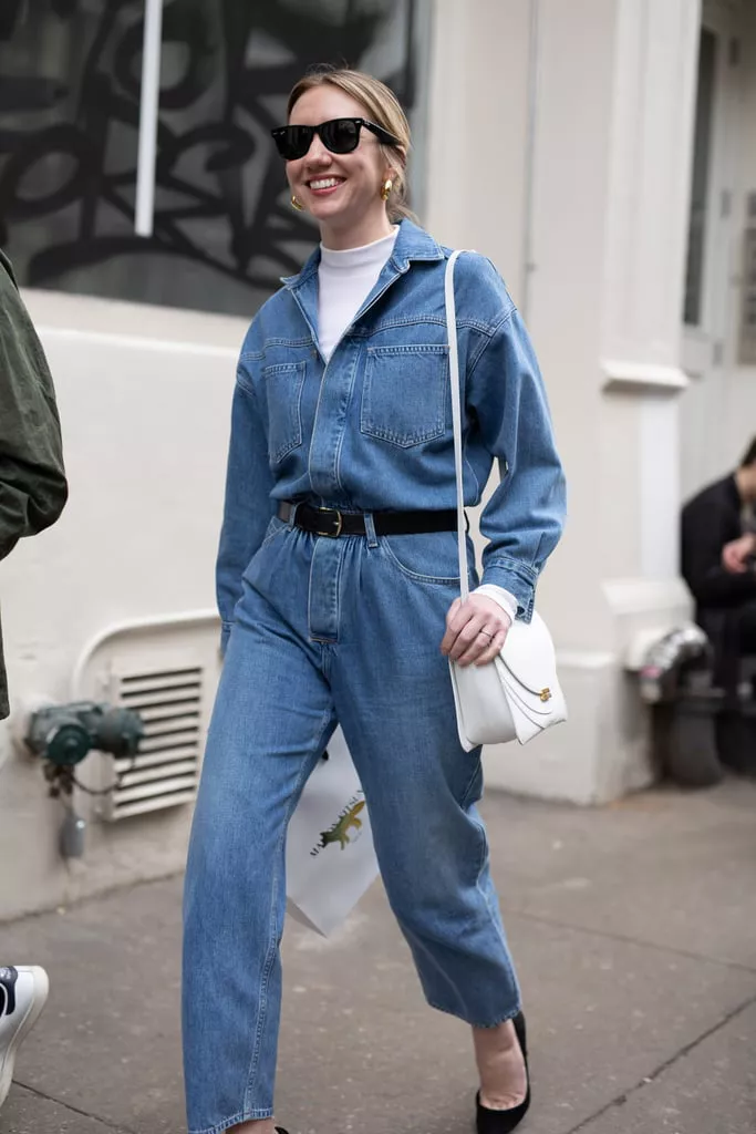 Девушка в синем джинсовом комбинезоне с ремнем и белая водолазка