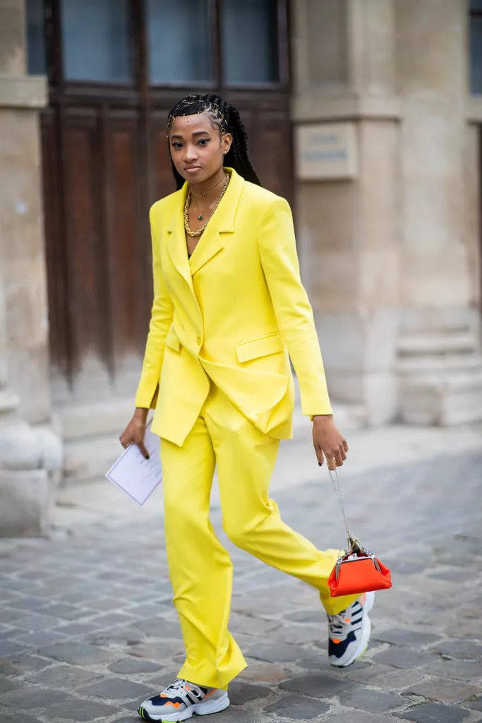 Девушка в желтом брючном костюме, кроссовки и мини сумочка