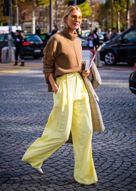 Девушка в желтых широких брюках, коричневый свитер