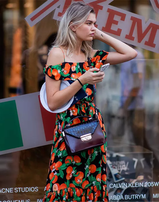 Девушка в платье с принтом томатов и текстурированной сумочкой