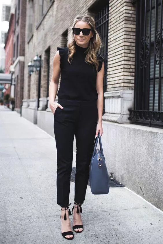 Девушка в черных брюках, топе и босоножках