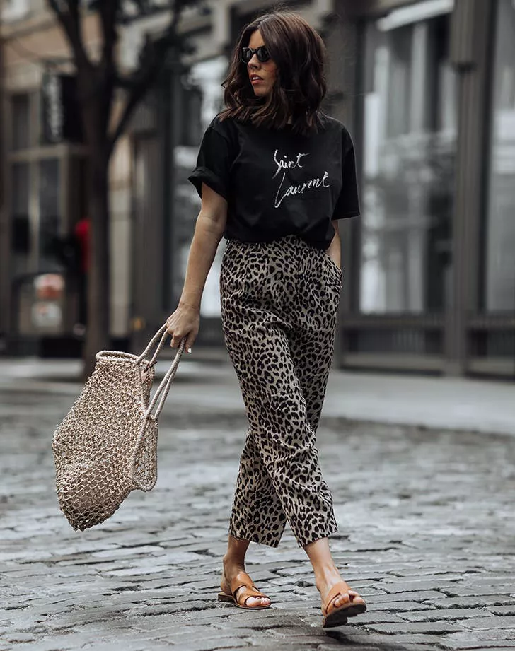 Девушка в брюках с леопардовым принтом, черная футболка и сланцы