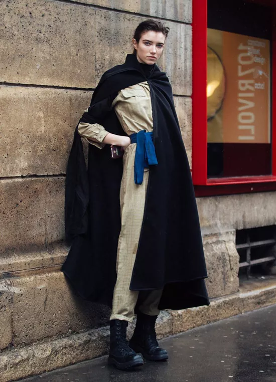 Девушка в черной накидке пальто, улитарный комбинезон и ботинки