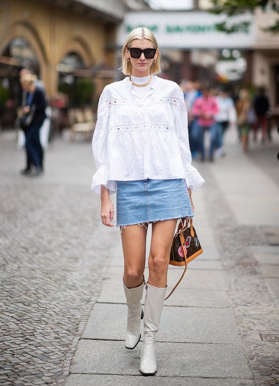 Девушка в джинсовой мини юбке, белая блузка и сапоги молочного цвета