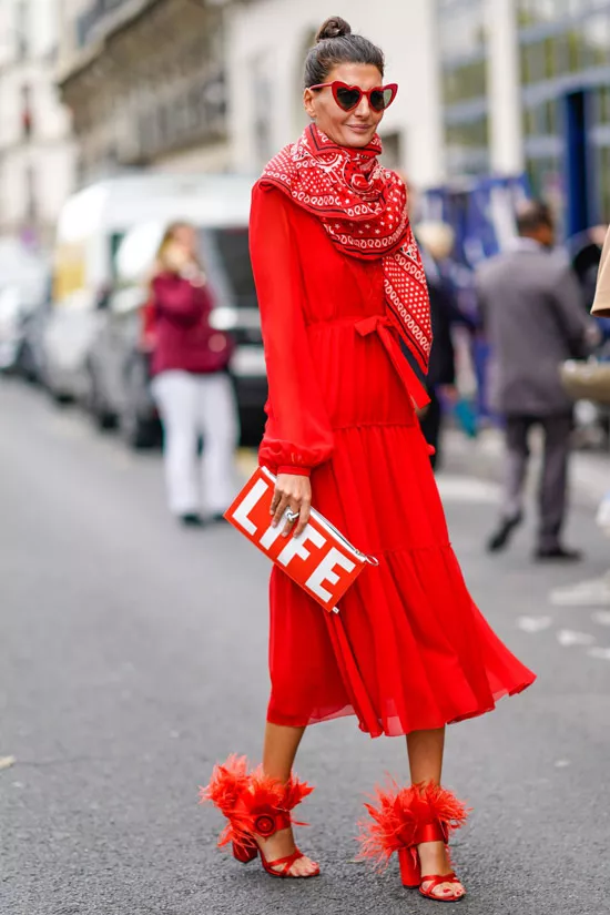 Девушка в красном платье с длинными рукавами, красные туфли на каблуке и клатч