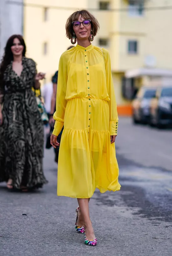 Девушка в легком желтом платье миди и разноцветных туфлях