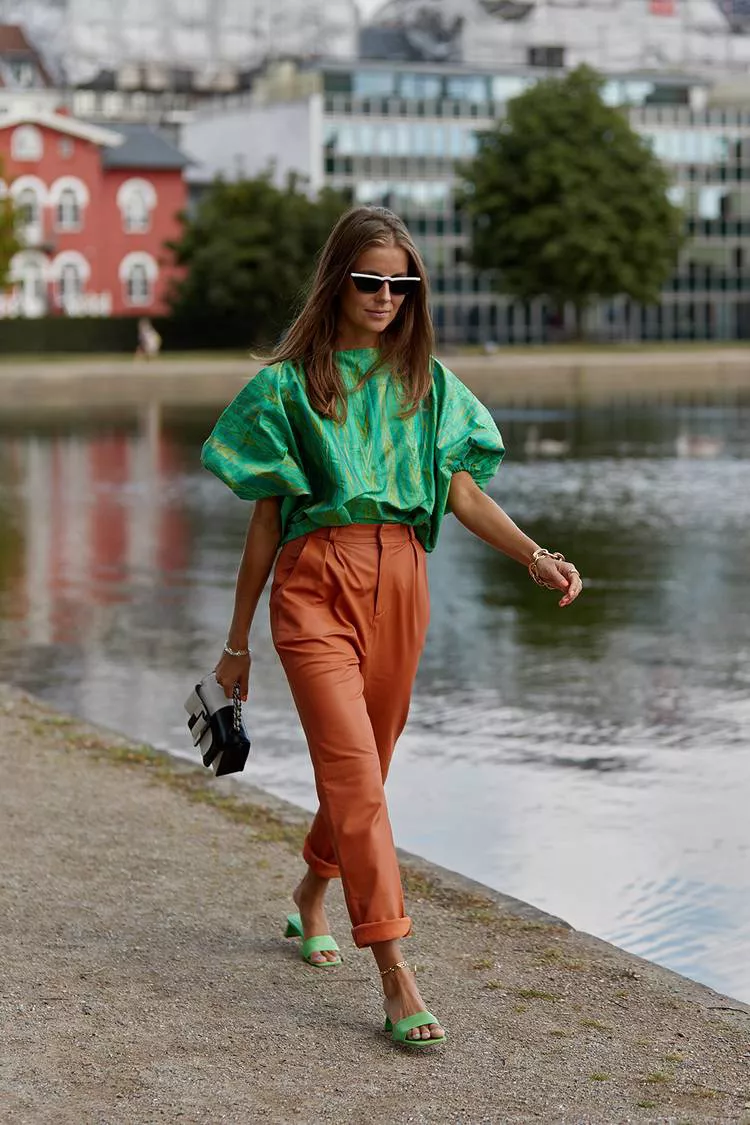 Девушка в оранжевых брюках, зеленая блузка и сандалии