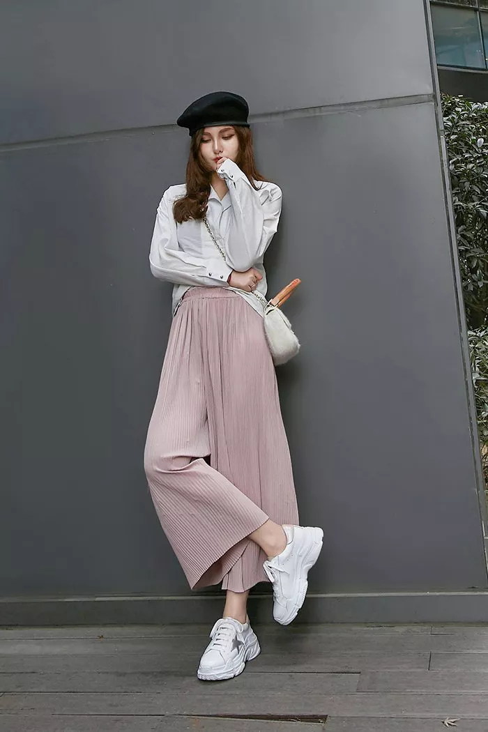 Девушка в розовых широких брюках, белая рубашка и кроссовки