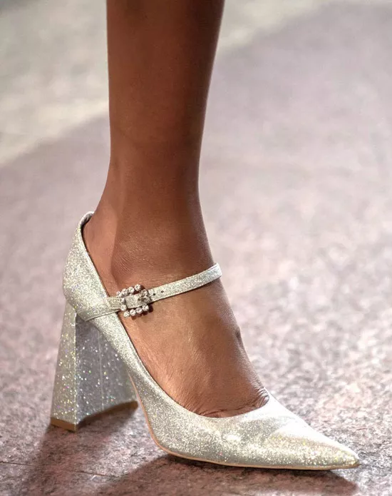 Модель в белых блестящих туфлях на каблуке