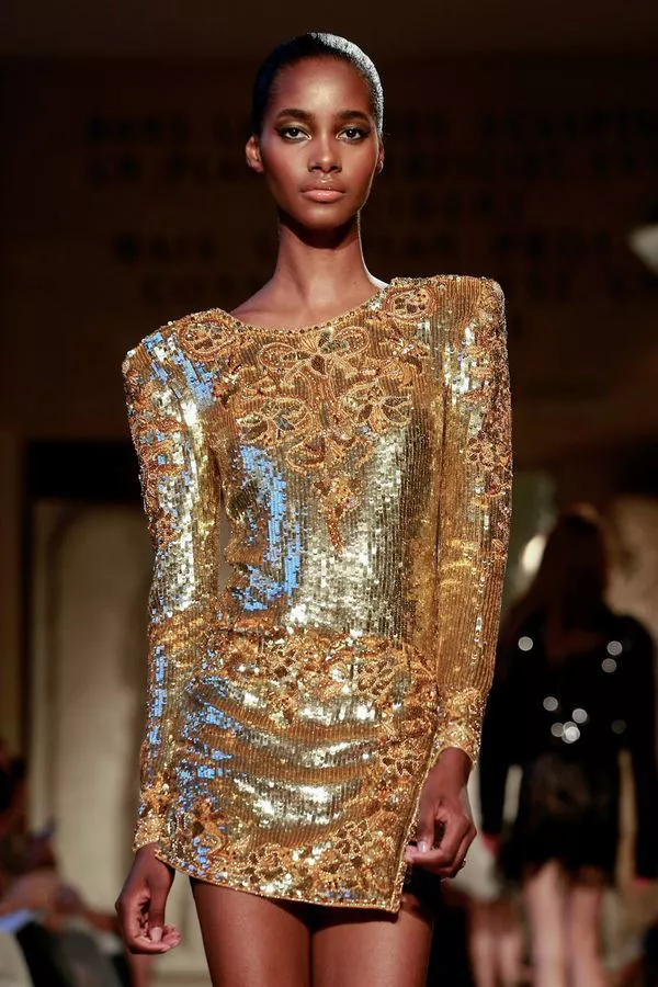 Модель в золотом мини платье с длинными рукавами