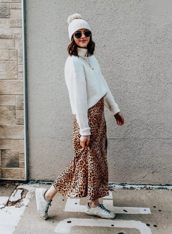 девушка в леопардовой юбке, белом свите, шапке и кедах