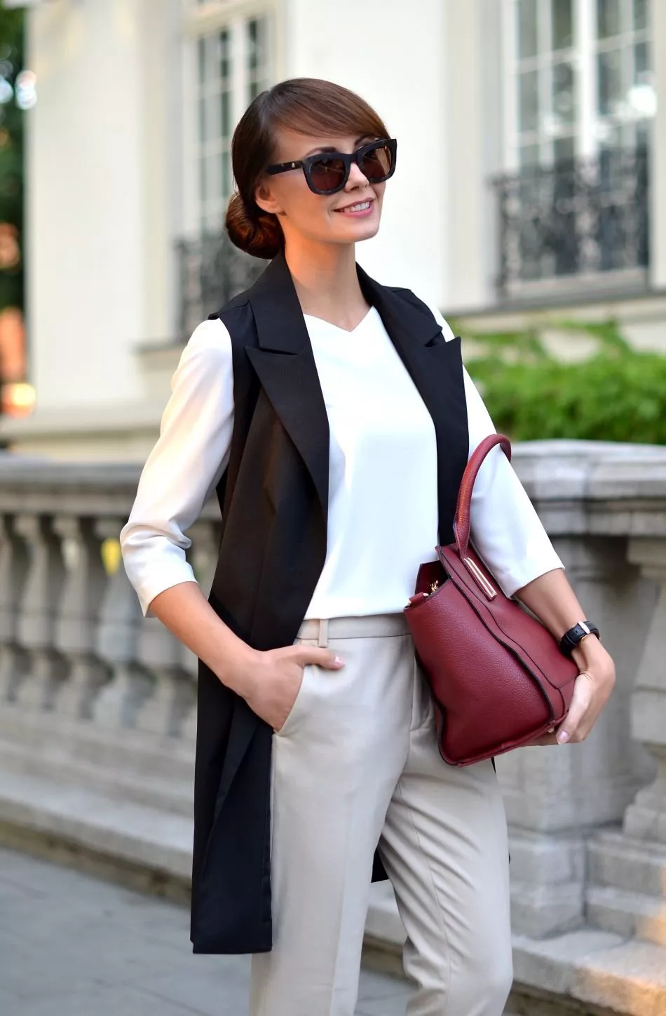 Девушка в белой блузке, бежевые брюки и черный удлиненный жилет