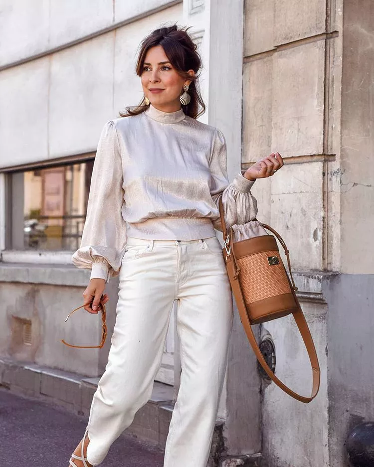 Девушка в белых джинсах, шелковая блузка с пышными рукавами и коричневая сумка ведро