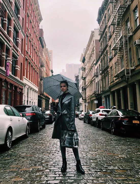 Девушка в кожаном плаще с поясом, черные ботинки и зонт