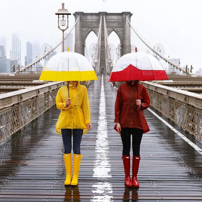Девушки в ярких желтых и красных резиновых сапогах, дождивиках и зонты