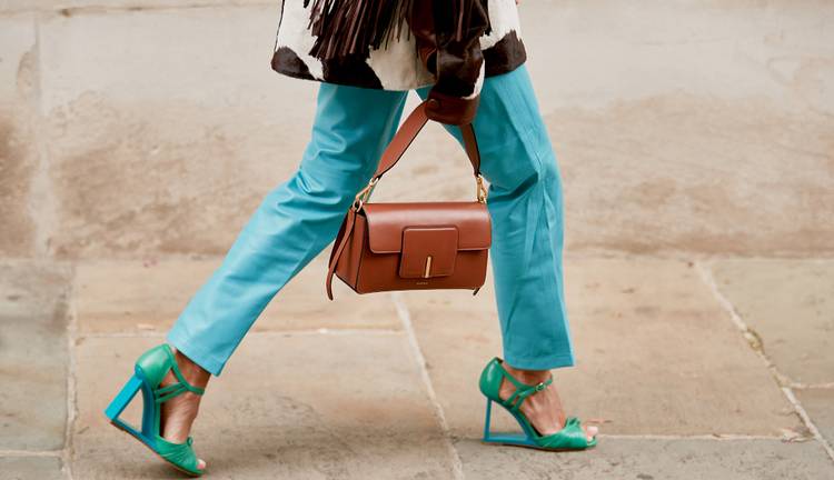 Девушка в голубых брюках, босоножки на каблуке и коричневая сумочка