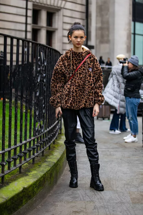 Девушка в кожаных брюках, полушубок с леопардовым принтом и черные грубые ботинки