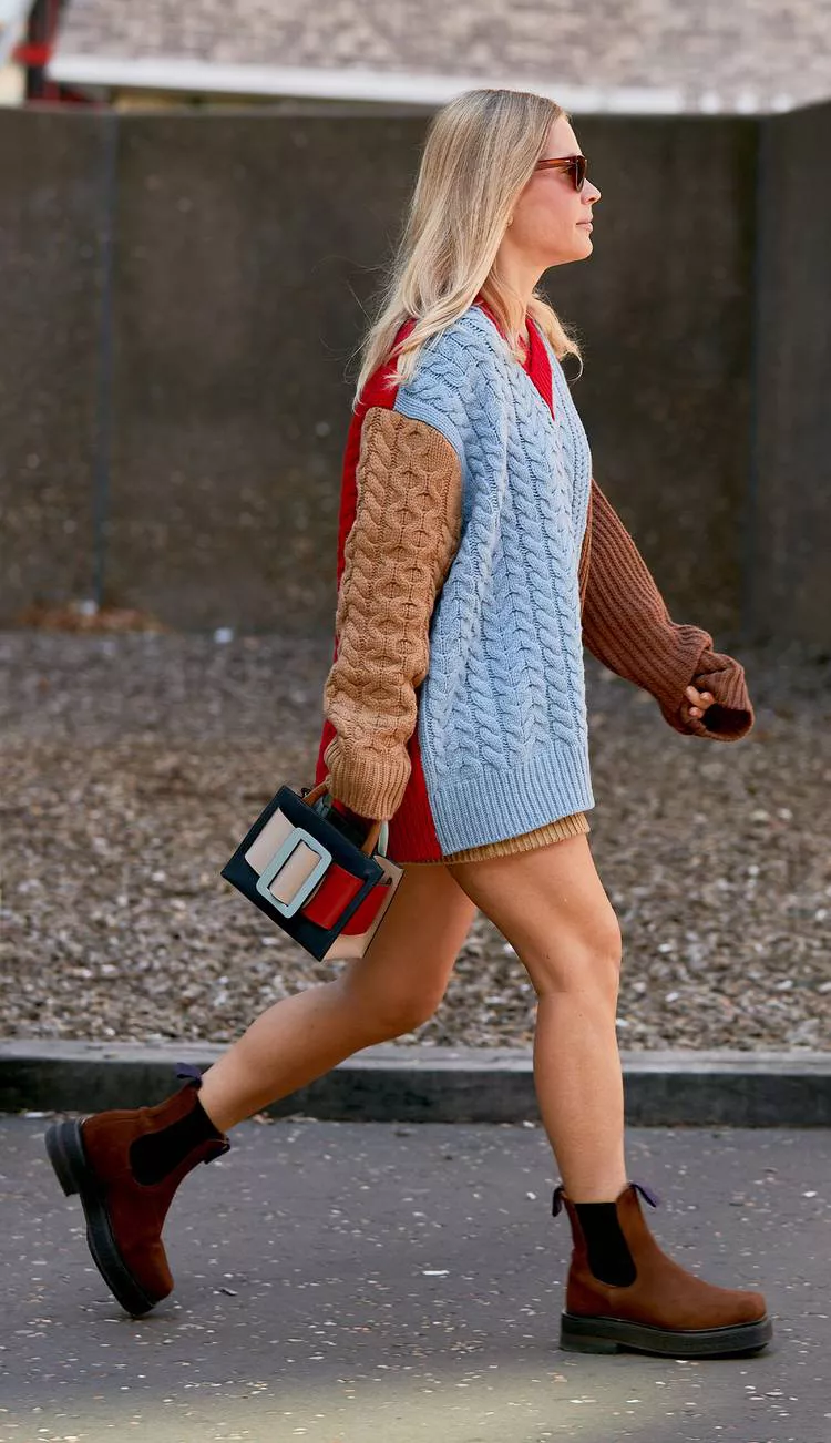 Девушка в разноцветном вязанном свитере, коричневые ботинки на плоской подошве и маленькая сумочка с пряжкой