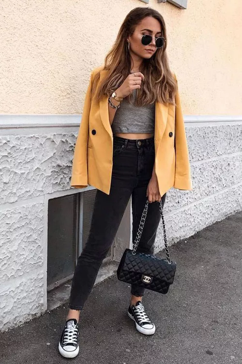 Девушка в серых джинсах с завышенной талией, кроп топ и желтый блейзер
