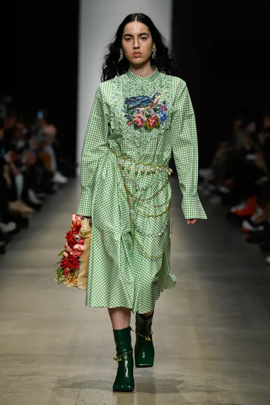 Девушка в зеленом платье миди в клетку с цепями и украшениями и зеленые ботильоны