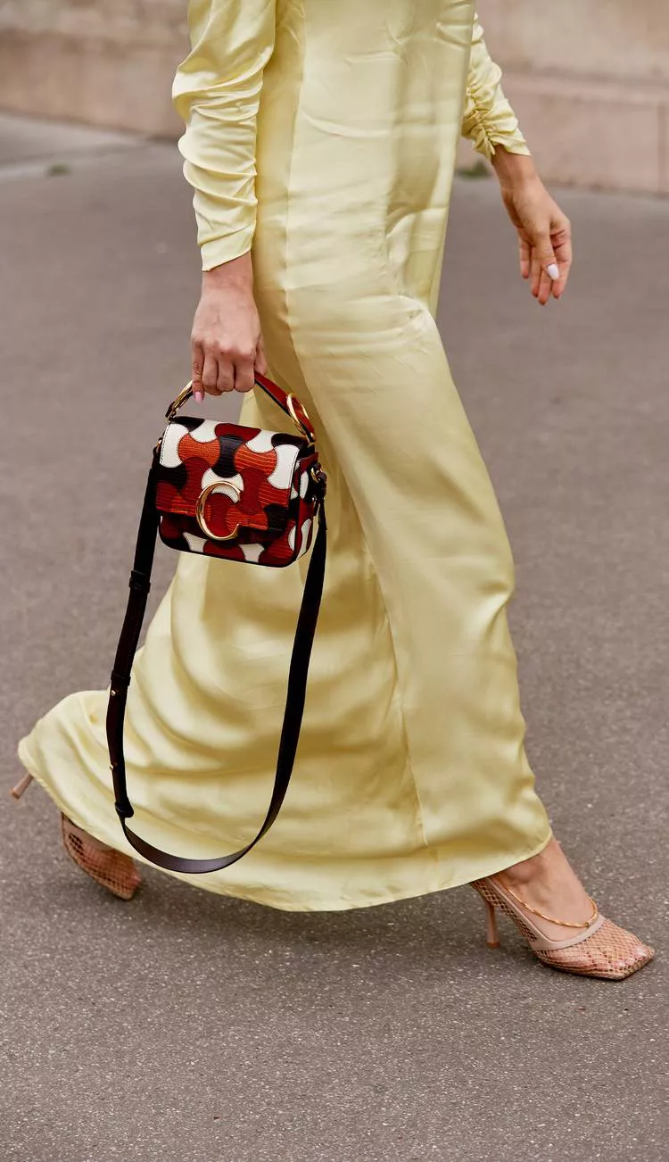 Девушка в желтом атласном платье, бежевые босоножки и сумочка