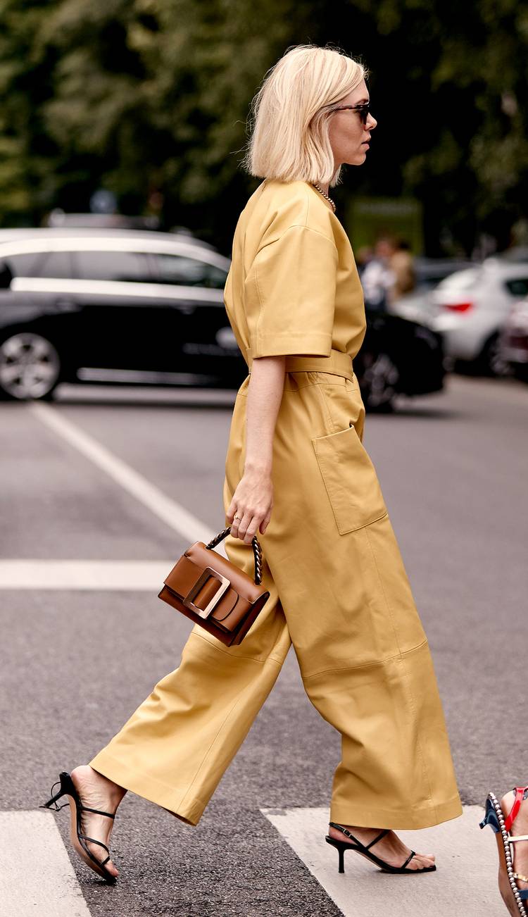 Девушка в желтом комбинезоне, черные босоножки и маленькая сумочка с пряжкой