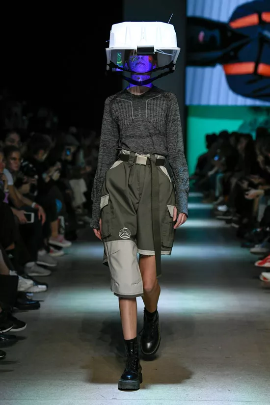 Модель с серых шортах с поясом, серая кофточка и ботинки