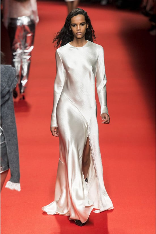 Модель в белом атласном платье до пола с длинными рукавами