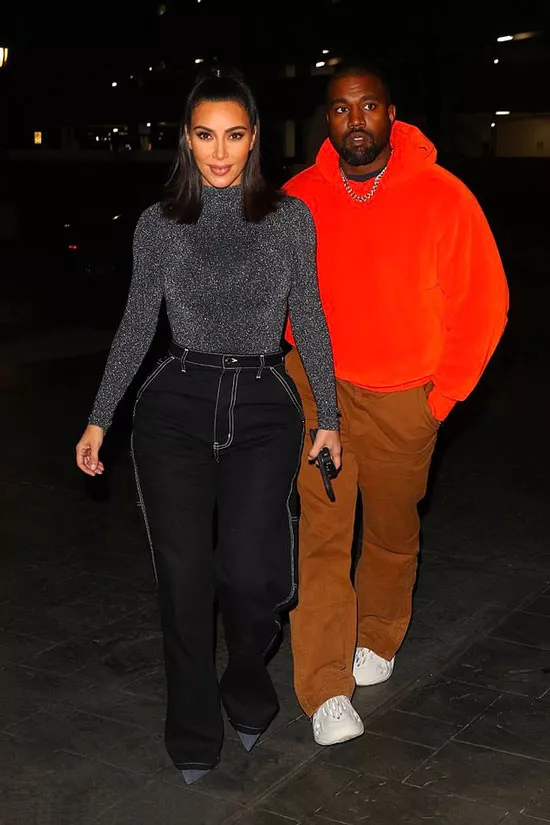 Ким Кардашьян в черных джинсах и Канье Уэст в оранжевой толстовке