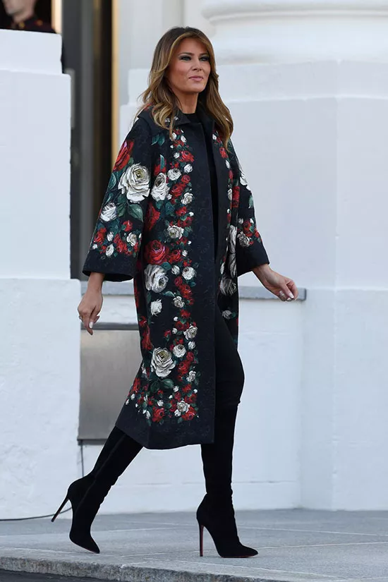 Мелания Трамп в черных брюках, сапогах и цветочном пальто