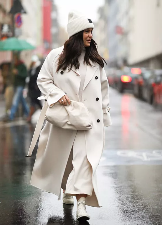 Девушка в белом длинном пальто, кроссовки и мягкая сумка