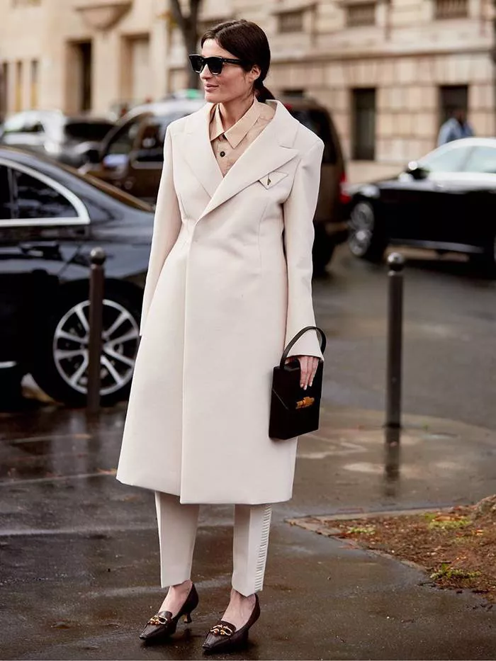 Девушка в белом пальто, брюки и туфли на невысоком каблуке
