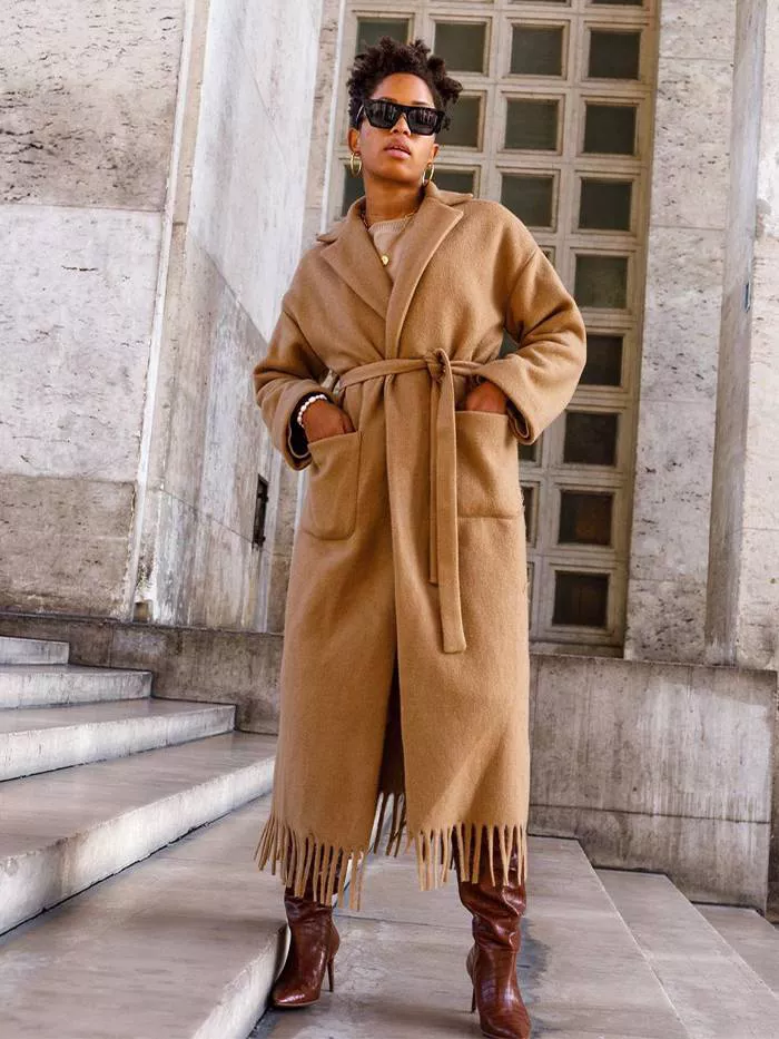 Девушка в бежевом пальто с поясом и коричневые сапоги