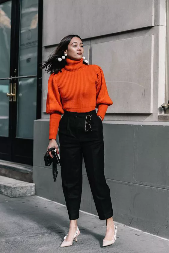 Девушка в черных брюках, оранжевый свитер и туфли