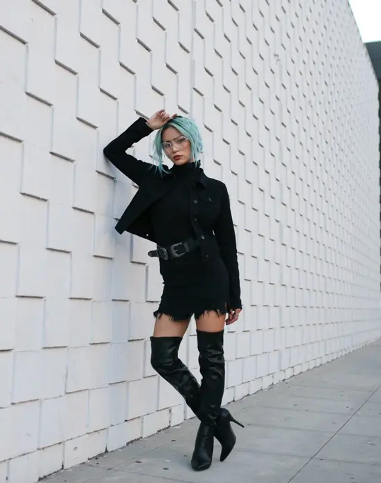 Девушка в черных кожаных ботфортах на каблуке, мини юбка с ремнем и черная водолазка