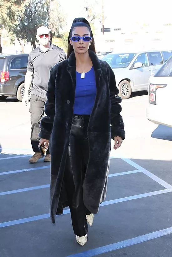 Ким Кардашьян в кожаных брюках, синем топе и плюшевом пальто