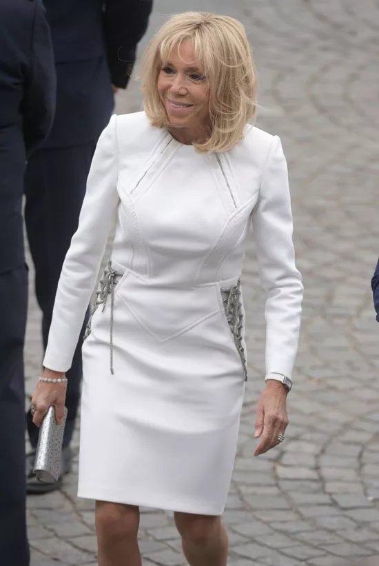 Брижит Макрон в белом платье с завязками по бокам и серебристым клатчем 14 июля 2019