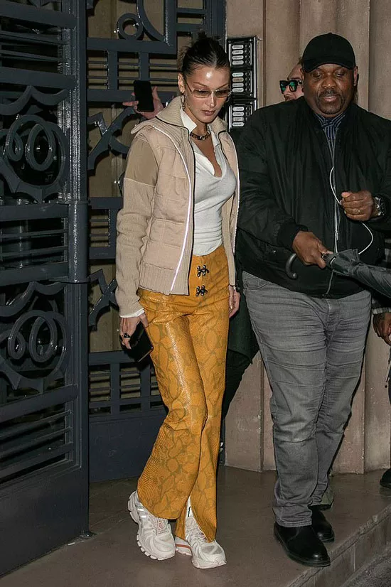 Белла Хадид в горчичных брюках с принтом питона и кремовых кроссовках
