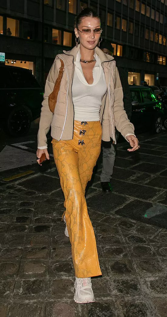 Белла Хадид в горчичных брюках с принтом питона, белом топе и кроссовках