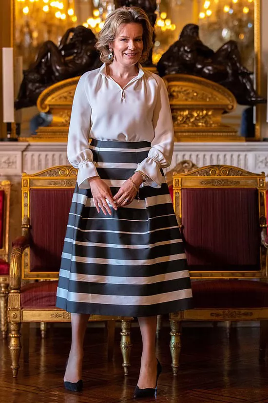 Бельгийская королева Матильда в белой шелковой блузе с манжетами и юбке миди в полоску