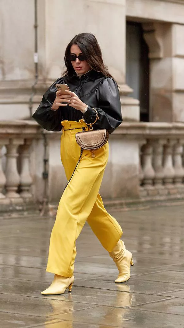 Девушка в прямых желтых брюках с завышенной талией, черная кожаная рубашка и желтые сапоги