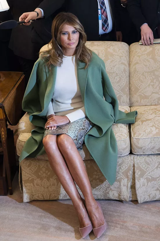 Мелания Трамп в белой блузе и зеленом пальто