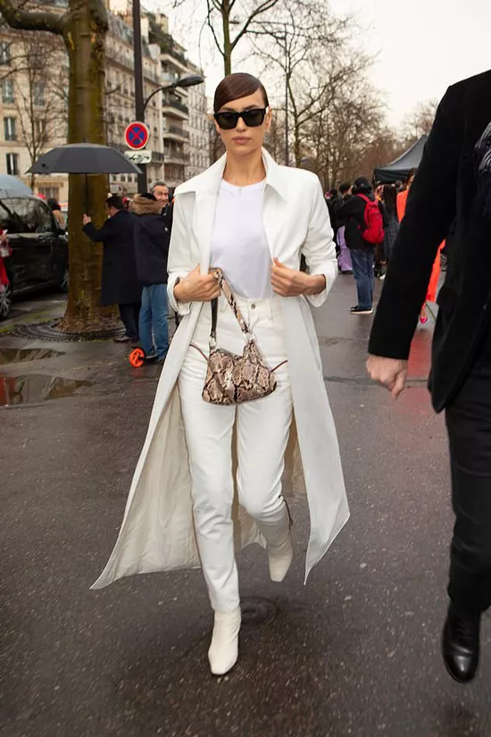 Ирина Шейк в белом наряде, очках и с сумкой под рептилию
