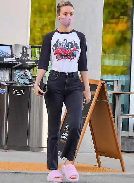 Бри Ларсон в джинсах, футболке с принтом и пушистых тапочках