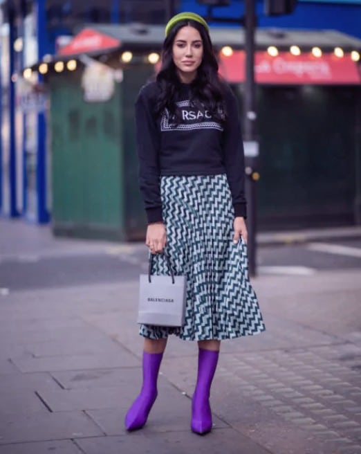 Девушка в юбке миди, черная толстовка и фиолетовые ботильоны