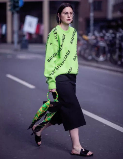 Девушка в зеленом свитере, черные укороченные брюки и простые шлепки