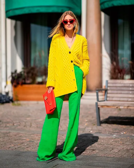 Девушка в просторных зеленых брюках, красная сумочка клатч и желтый кардиган