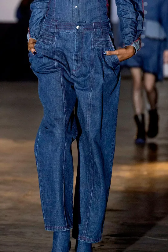 Модель в синих свободных джинсах и джинсовой рубашке темного цвета
