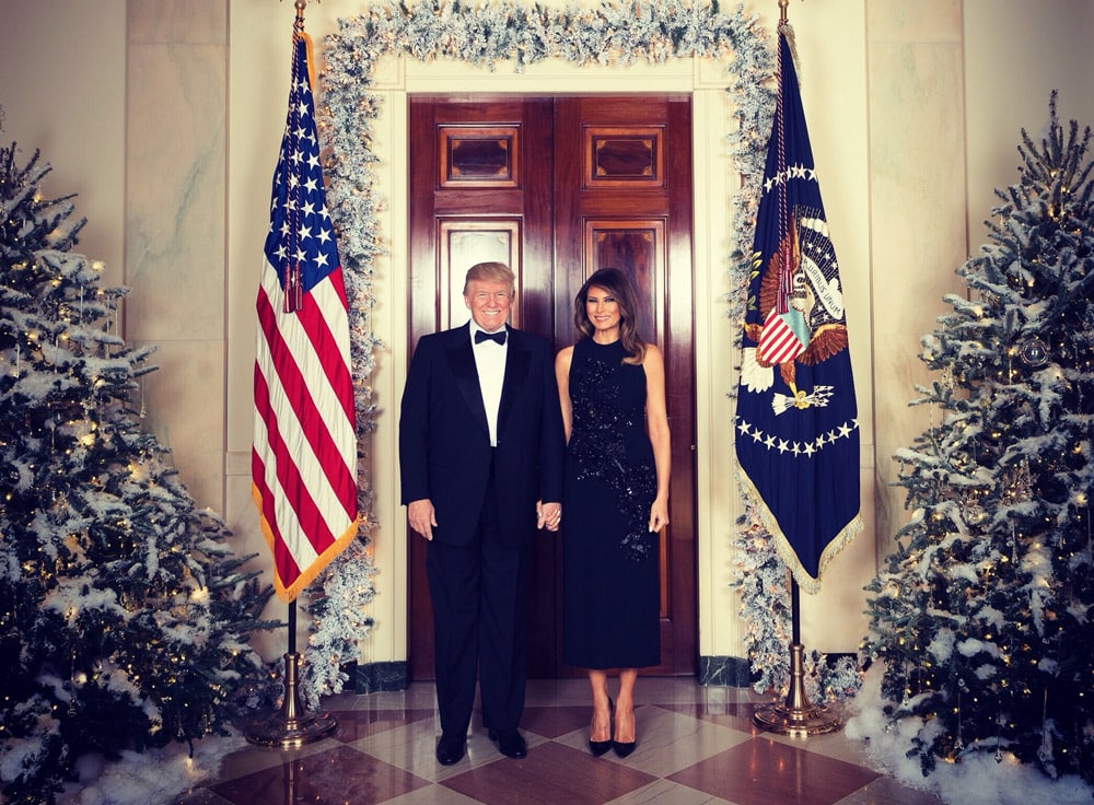 Мелания Трамп в черном платье рукавами на фоне новогодней елки