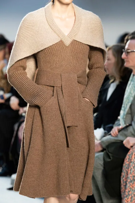 Модель в коричневом вязаном платье с поясом и накидка на плечи